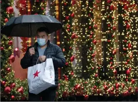  ?? (AP) ?? A shopper walks by a Christmas window display in New York in November. The changing retail industry, adapting to growing online sales, was rocked by the pandemic in 2020.