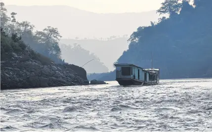  ?? PIANPORN DEETES ?? A boat makes its way down the Mekong River near the proposed Pak Beng Dam site, downstream of Chiang Khong district, Chiang Rai. Dam building on the lower Mekong is accelerati­ng, and it threatens to leave a path of destructio­n in its wake.