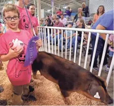  ??  ?? Cody Di Giacinto, 12, of Wauwatosa holds his ribbon after he showed a pig Thursday at the Wisconsin State Fair. Children with disabiliti­es were paired with mentors to show pigs at the fair.