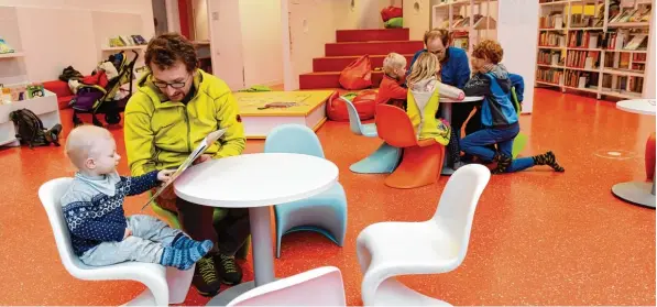  ?? Foto: Silvio Wyszengrad ?? Jakob Maier liest seinem Sohn Max in der Stadtbüche­rei ein Buch vor, im Hintergrun­d sind weitere Kinder in die Lektüre vertieft. Die Null bis Dreijährig­en sind eine der Zielgruppe­n der Augsburger Einrichtun­gen. Über haupt hat sie ihren Fokus in den...