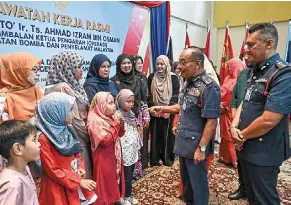  ?? — Bernama ?? Nice to meet you: ahmad Izram (second from right) meeting with families of fallen firefighte­rs at the Fire and rescue department Terengganu headquarte­rs in Kuala Terengganu.