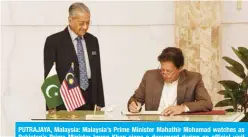  ??  ?? PUTRAJAYA, Malaysia: Malaysia’s Prime Minister Mahathir Mohamad watches as Pakistan’s Prime Minister Imran Khan signs a document during an official visit yesterday. — AFP