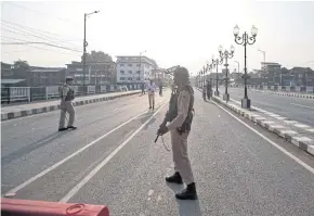  ?? REUTERS ?? Indian security personnel stand guard on a deserted road during restrictio­ns in Srinagar, the largest city of the Indian state of Jammu and Kashmir, on Monday.