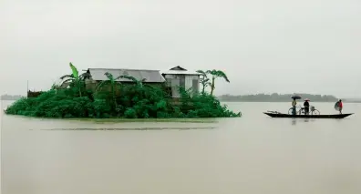  ?? AFP ?? Villagers paddle their country boat at the flood affected Pokoriya village, near Guwahati, Assam, on Friday. —