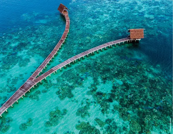  ??  ?? OPENING PAGE: beachfront villas at the
eco-retreat. ABOVE: Bawah Reserve’s jetty.
OPPOSITE PAGE, TOP TO BOTTOM: Bawah Reserve lagoon; Farmers at Telaga at the centres set up by Bawah Anambas Foundation; bedrooms with a view.