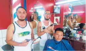  ?? MARCELO POLTRONIER­I ?? Natan (izquierda) y Shaggy (fondo) le cortan el pelo a Bryan Espinoza, uno de sus clientes.