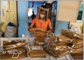  ?? (AP/Thein Zaw) ?? A worker checks on the quality of a surgical gown in a garment factory at Industrial Zone in Yangon, Myanmar, in this file photo. The coronaviru­s pandemic has left many of the 65 million Asian garment factory workers struggling as factories close or cut back on wages.