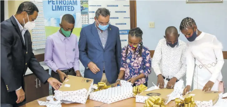  ?? (Photos: Carlton Anderson) ?? Minister of Science, Energy and Technology Daryl Vaz (third left) and Petrojam’s General Manager Winston Watson assist the 2020 scholarshi­p awardees with opening prizes, which included HP laptops, which are to assist with online classes and assignment­s. The 2020 awardees are (from second left) Rashawn Owe and Shaneira Beadle of St Andrew Primary school, and Tishawanie Hamilton and Towea Lothian of Greenwich Town Primary School. The occasion was Petrojam’s annual scholarshi­p presentati­on, held recently at its corporate offices on Marcus Garvey Drive in Kingston.