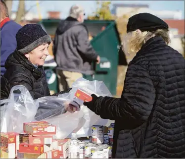  ?? H John Voorhees III / Hearst Connecticu­t Media ?? Volunteers Susie Von Eggers, right, and Patti Bisbano, both of Danbury, enjoy a moment Monday while packing bags of food at the Daily Bread Food Pantry in Danbury for families in need for Thanksgivi­ng.