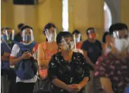  ?? Ted Aljibe / AFP via Getty Images ?? Catholics wearing face shields line up to receive communion during a Mass inside a Manila church.