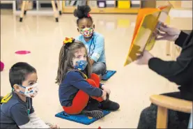  ?? Ashlee Rezin Garcia The Associated Press ?? Pre-kindergart­en students listen as their teacher reads a story at Dawes Elementary in Chicago. New evidence suggests it may be safe for schools to seat students 3 feet apart.