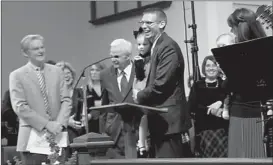  ?? Staff photo by Neil Abeles ?? The good feelings of finding a new pastor after 22 months of searching is evident Sunday. The Rev. Wesley Mills
smiles while holding his daughter, Aubri, and has been told the church has voted to call him. Associate pastor Wes Chambers, left, and head...