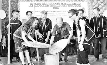  ??  ?? Deputy Chief Minister Datuk Seri Wilfred Madius Tangau filling paddy into a ‘lesung’ as a symbolic gesture at the launching of the Pesta Kaamatan celebratio­n at Kampung Bongol near here on Thursday. - Bernama photo