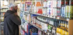  ?? RICK KAUFFMAN — DIGITAL FIRST MEDIA ?? A shopper at Giant Food Stores in Havertown pores over the selection of six-pack beers. By Tuesday, any beer distributo­r in Pennsylvan­ia may sell beer individual­ly or divide cases into six-packs.