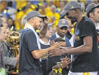  ?? FOTOS: IMAGO, DPA ?? Erst die Freude, dann die Trophäe: Stephen Curry (li.) und Kevin Durant sind auf dem Gipfel.