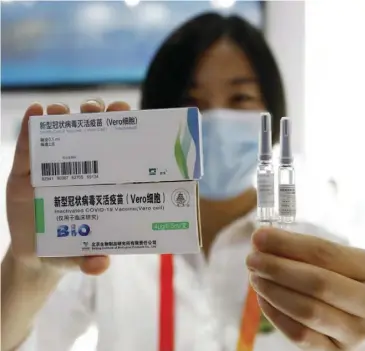  ??  ?? A Chinese health official shows the Covid-19 vaccine made in that country.