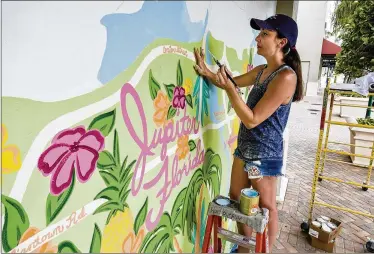  ?? RICHARD GRAULICH / THE PALM BEACH POST ?? Artist Melissa Rinaldi paints a map of Jupiter at Harboursid­e Place. Rinaldi, 35, has been operating out of her 118 Coastal Way location for nearly a year.