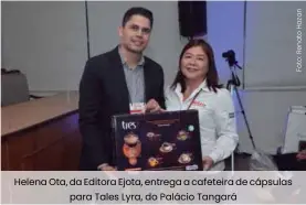  ??  ?? Helena Ota, da Editora Ejota, entrega a cafeteira de cápsulas para Tales Lyra, do Palácio Tangará