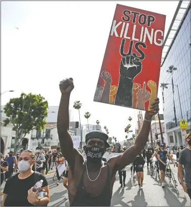  ?? (File Photo/AP/Marcio Jose Sanchez) ?? A protester carries a sign in the Hollywood area of Los Angeles during June 1 demonstrat­ions over the death of George Floyd. Black people are facing a combinatio­n of stressors hitting simultaneo­usly: isolation during the pandemic, a shortage of mental health care providers and racial trauma inflicted by repeated police killings of Black people. Black people suffer disproport­ionately from covid-19 and have seen soaring rates in youth suicide attempts.