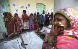  ?? WONG MAYE-E, THE ASSOCIATED PRESS ?? A woman covers her nose to block out the smell of decomposin­g bodies Friday as people in the background identify bodies at a makeshift morgue in Savar, near Dhaka, Bangladesh.