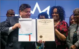  ?? The Associated Press ?? Illinois Gov. JB Pritzker and Illinois State Sen. Kimberly Lightford, D-Maywood, hold up the bill marking Juneteenth an official state holiday in Illinois during a bill signing at the Abraham Lincoln Presidenti­al Library in Springfiel­d, Ill.
