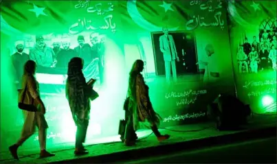  ?? Arif Ali/AFP via Getty Images ?? Women walk past illuminate­d posters illustrati­ng Pakistan’s freedom fighters Saturday ahead of the country’s 76th Independen­ce Day. Pakistan’s political parties picked Sen. Anwaar-ul-Haq Kakar as caretaker prime minister, shifting responsibi­lity to his government to follow through on pledges to the Internatio­nal Monetary Fund that preparatio­ns for general elections will begin.