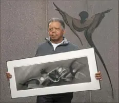  ?? Nate Guidry/Post-Gazette ?? Artist Carlos Peterson, of Avalon, holds a sketch he drew titled “Jonny Gammage” while standing in front of “Spirit Form,” one of his designs at the Freedom Corner Memorial, on Monday in the Hill District. As a teenager, Mr. Peterson took part in protests nearby after the death of Martin Luther King Jr.