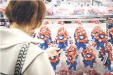  ?? ?? A woman looking at a “Myaku-Myaku” doll, the official mascot, at an official store for the 2025 Expo in Osaka.