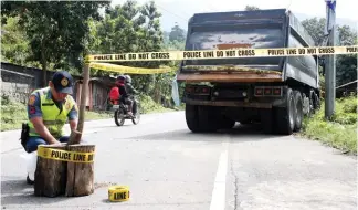  ?? Photo by Jean Nicole Cortes ?? ACCIDENT. A police officer from Pugo, La Union rolls out a police line around the truck which was hit by a Victory Liner bus at 4 a.m. on October 25 along the Aspiras – Palispis Highway (Marcos Highway) in Barangay Palina. The bus was removed earlier to make the road passable.