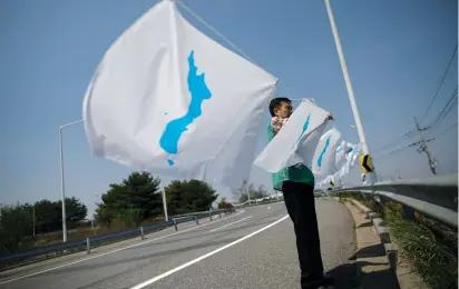  ?? (Kim Hong-Ji/Reuters) ?? A MAN HANGS a unificatio­n flag on the Grand Unificatio­n Bridge which leads to the Peace House, near the demilitari­zed zone separating the two Koreas in Paju, South Korea, yesterday.