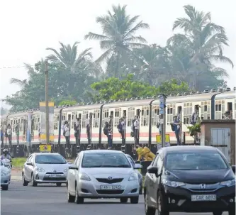  ??  ?? COLOMBO: Sri Lankans passengers hold on to door handles as they travel in a full carriage of a train in Colombo yesterday. Due to its affordabil­ity, train travel is a popular mode of transport in this nation of 20 million people.