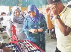  ??  ?? Rohani (centre) helps an elderly man to choose the frame for his new glasses.