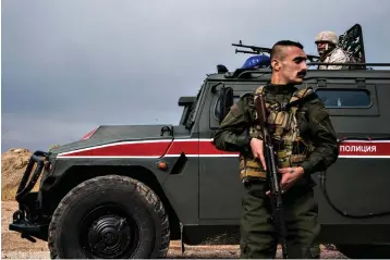  ?? Associated Press ?? ■ A member of Asayish, or the Internal Security Forces, stands guard Friday by a Russian military vehicle during a patrol near the Syrian and Turkish border.