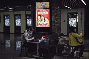  ?? Associated Press ?? People wearing face masks to help curb the spread of the coronaviru­s wait for their movies at Poly Cinema in Beijing on Thursday.