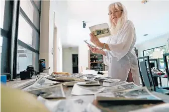  ?? AMY BETH BENNETT/SUN SENTINEL PHOTOS ?? Monique Bourassa Fuchs looks over photos from the Vietnam War era that workers found above her kitchen while doing repairs at her Lighthouse Point home. She tracked down the owner, Robert Wells, 74, living in Delray Beach.