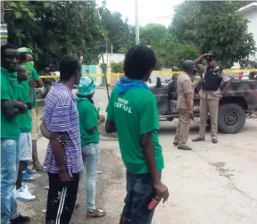  ??  ?? Jamaica Labour Party supporters look on as the police secure the area where their motorcade was attacked yesterday, leaving one person dead.