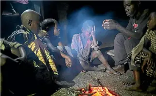  ?? PHOTO: REUTERS ?? People gather around a fire in Kagorwa Pygmy camp on Idjwi island in the Democratic Republic of Congo. There are no more than 7000 of them.