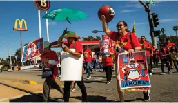  ?? Mel Melcon/los Angeles Times ?? Fast food workers cross 3rd Street in East Los Angeles after holding a rally outside of a Mcdonald’s restaurant, background, to raise awareness of their push for better working conditions, on July 13, 2023.