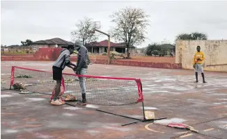  ??  ?? After a light thundersho­wer boys prepare to play tennis in Thomo village near Giyani in Limpopo.