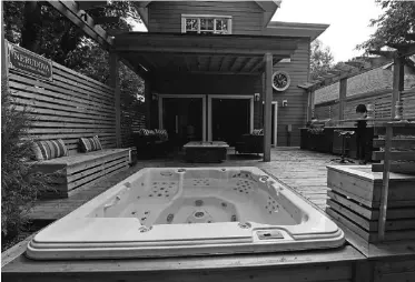  ??  ?? Sheltered under mature trees on the cedar deck is a hot tub that beckons year round.
