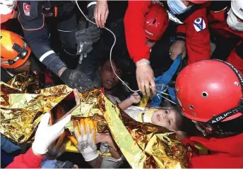  ??  ?? Rescue workers carrying 3-year-old Ayda Gezgin out of the rubble.