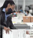  ?? JESSICA MCGOWAN/GETTY IMAGES ?? A Gwinnett County worker processes absentee and provisiona­l ballots at the Gwinnett Voter Registrati­ons and Elections office in Lawrencevi­lle, Ga., on Nov. 6.