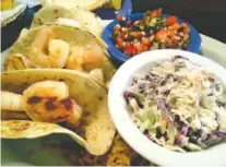  ?? PHOTOS BY SUSAN PIERCE ?? Four grilled shrimp are served in each of three tacos with sides of homemade coleslaw, pico de gallo and rice.