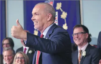  ?? CHAD HIPOLITO/THE CANADIAN PRESS ?? Premier John Horgan gives a thumbs up after he was sworn-in as premier. Health Minister Adrian Dix, one of two health ministers appointed Tuesday, grins over Horgan’s right shoulder.