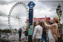  ?? Tolga Akmen / AFP via Getty Images ?? Tourists take pictures on Westminste­r Bridge with the London Eye in the background in central London on Friday.