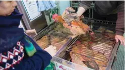  ??  ?? HONG KONG: A shop owner shows a customer a live chicken for sale in the Wanchai markets of Hong Kong. —AFP