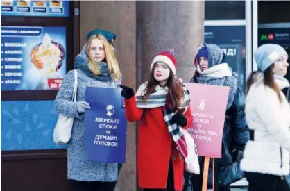  ?? Agence France-presse ?? Three Ukrainian students hold placards reading ‘Keep calm and think with your head’ and ‘Keep calm and embrace those who are near’ during the action called ‘Keep Calm’ in Kiev, Ukraine, on Wednesday.