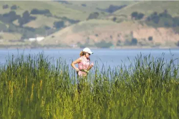  ?? Paul Chinn / The Chronicle ?? A woman jogs on a trail along the bay at Radke Martinez Regional Shoreline Park in Martinez during the heat wave. But East Bay and elsewhere in the region temperatur­es are to drop 10 to 20 degrees.