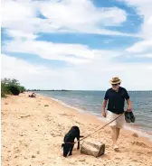  ?? JEFF HOLLAND ?? Jeff Holland and Millie stroll an almost deserted beach at Terrapin Nature Area on Kent Island. The park offers views that are a mirror image of the ones from Sandy Point State Park across the Chesapeake Bay.
