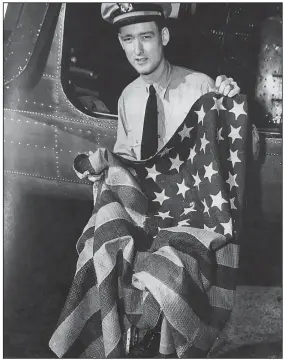  ??  ?? Lt. John K. Bremyer holds the Perry flag, which caused him to miss a date with his steady girl but allowed him to share a date with history.
(Formal Surrender of the Japanese Empire on the Battleship Missouri, featuring the Perry flag)